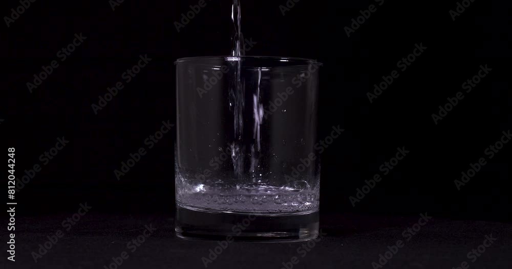 Slow motion shot of water pouring into glass on black background. Slow motion shot of water pouring into glass on black background.
