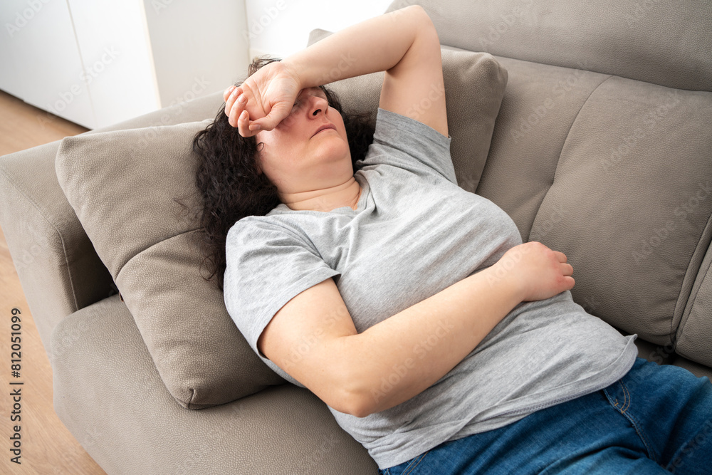 Woman lying on back on comfortable couch at home, covering eyes with hand, sleeping at daytime, feeling tired, enjoying relaxation, leisure, break, weekend. Top view Woman lying on back on comfortable couch at home, covering eyes with hand, sleeping at daytime, feeling tired, enjoying relaxation, leisure, break, weekend. Top view