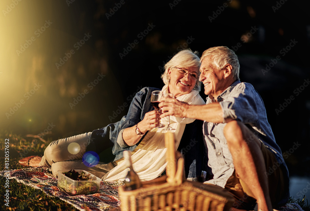Fototapeta premium Senior couple, wine glasses and toast at picnic on travel, romance and relax in outdoor nature. Elderly people, cheers and drink alcohol on vacation, holiday and calm celebration on anniversary