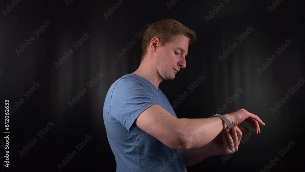 a stylish young man deliberately fastens an elegant timepiece around his wrist on the minimal black backdrop. His purposeful movements exude an unmistakable air of poise and man-of-the-world flair a stylish young man deliberately fastens an elegant timepiece around his wrist on the minimal black backdrop. His purposeful movements exude an unmistakable air of poise and man-of-the-world flair