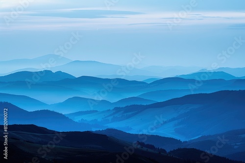 Scenic Mountain Range at Sunset. Rolling Hills and Rugged Peaks Silhouetted Against Blue Sky photo