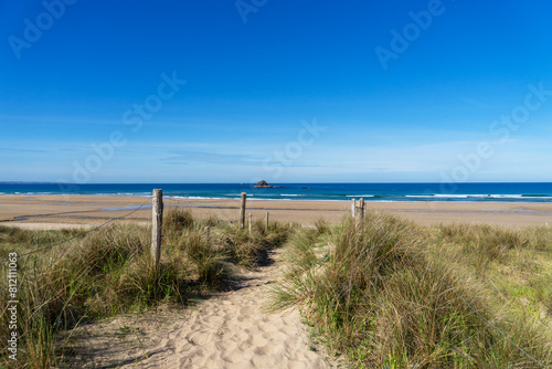 Sentier serpentant    travers les dunes  offrant une vue d  gag  e sur la plage et la mer d Iroise  une balade apaisante au c  ur de la nature pr  serv  e de la presqu   le de Crozon.