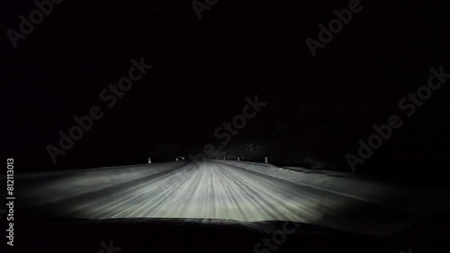 Driving on snowy road at night in forest.