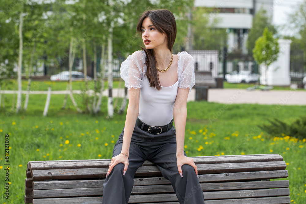 Young woman sitting on a bench in a summer park