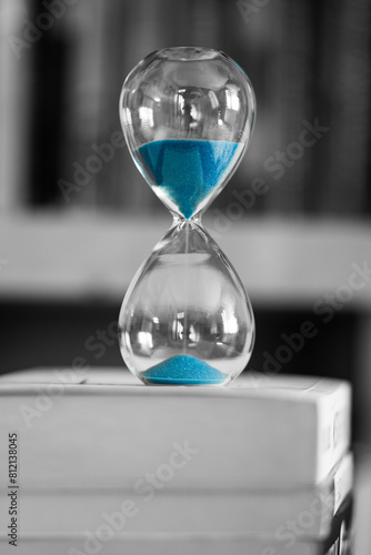 Blue sand hourglass on books background