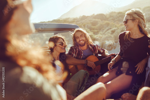 Young friends enjoying music and road trip with guitar in pickup truck photo