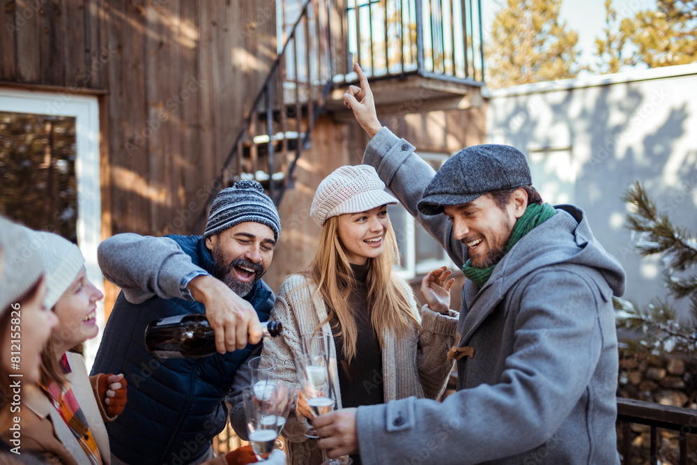 Friends laughing and drinking champagne in a winter outdoor gathering Friends laughing and drinking champagne in a winter outdoor gathering