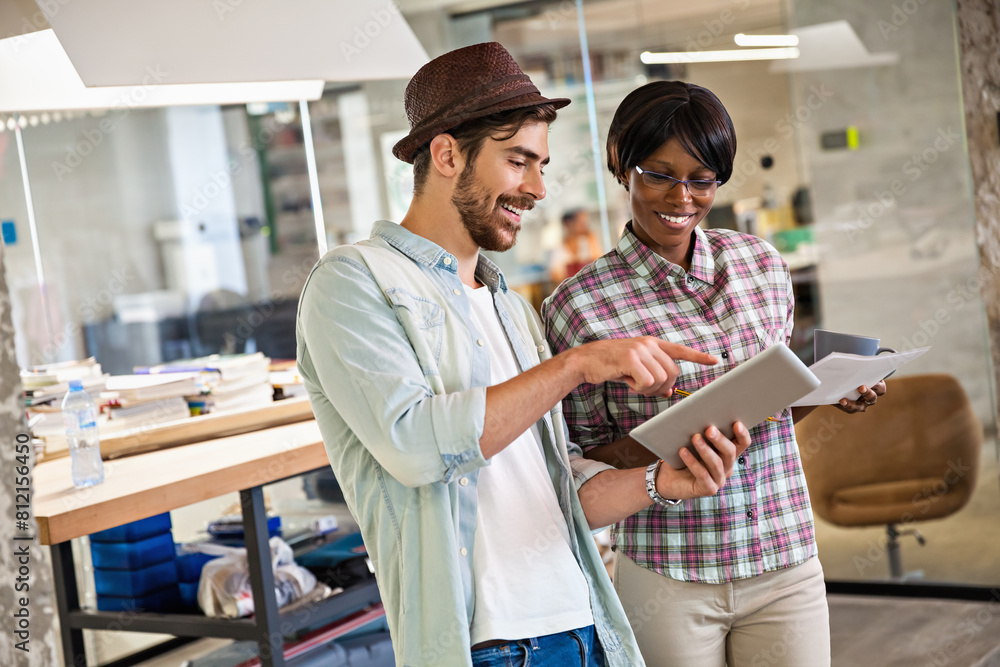 Obraz premium Two diverse young office workers using tablet together