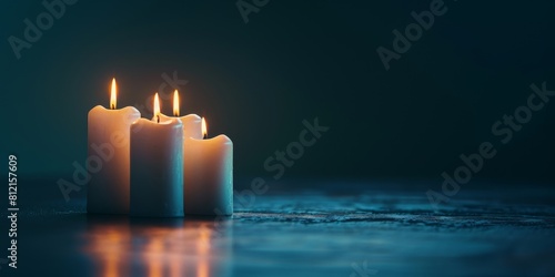 Four white candles are burning on a dark blue background photo