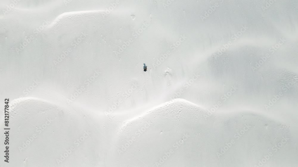 Aerial top view of young lonely man in desert with white sand dunes. Aerial top view of young lonely man in desert with white sand dunes.