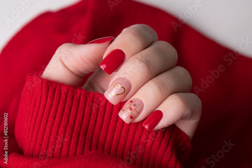 
Beautiful female hand with red manicure nails, heart and Valentine's day design
