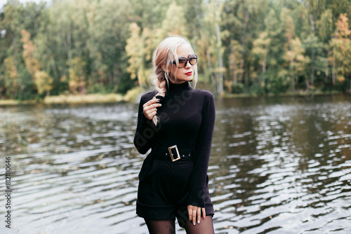 Young beautiful fashion woman in stylish black clothes staying near the river
