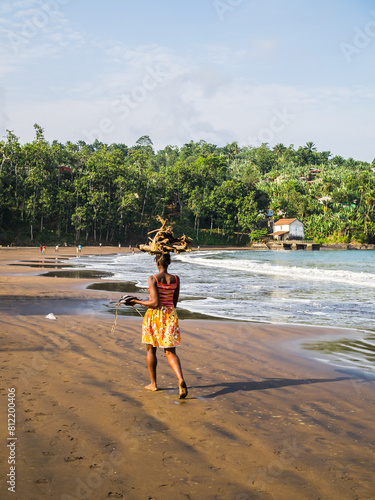Obraz na płótnie Using the beach as a road and carrying wood for fire on the head w salonie