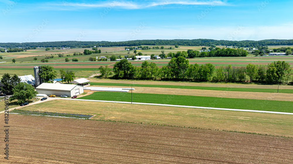 Aerial shot capturing serene beauty of rural farm, mix of plowed fields, green crops, farm buildings Aerial shot capturing serene beauty of rural farm, mix of plowed fields, green crops, farm buildings