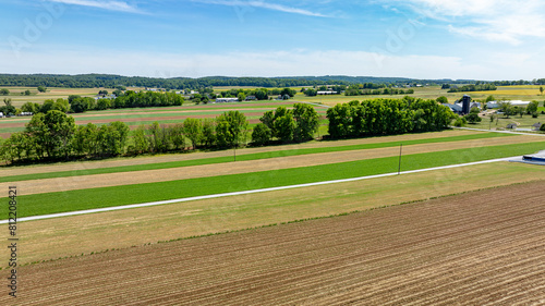 Aerial perspective of diverse rural farmland, highlighting patterned crop fields, trees, and farm