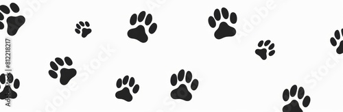 Seamless and minimalist background pattern featuring black animal paw prints scattered irregularly on a clean white backdrop, perfect for pet-related designs and decorative purposes