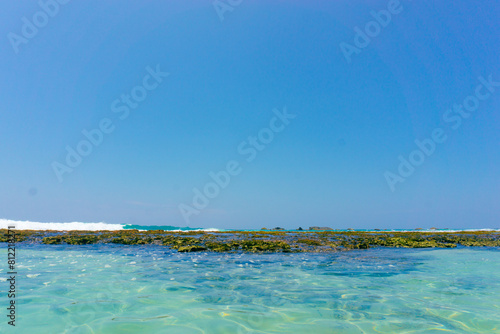 Canvas Print A strip of large stones and boulders goes into the sea, fencing the sandy beach