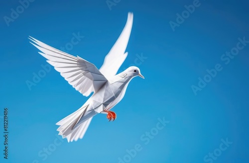 white pigeon made of paper on a blue background. The dove of peace. An origami figurine.