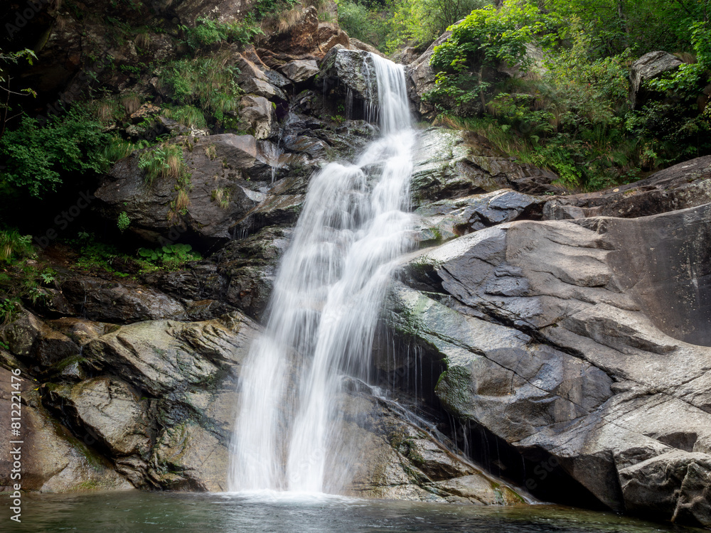Obraz premium Long exposure shot of a beautiful waterfall formed by the Burdeiver creek. Surrounded by rocks and trees near Fondo in Valchiusella, Piemonte, Italy.