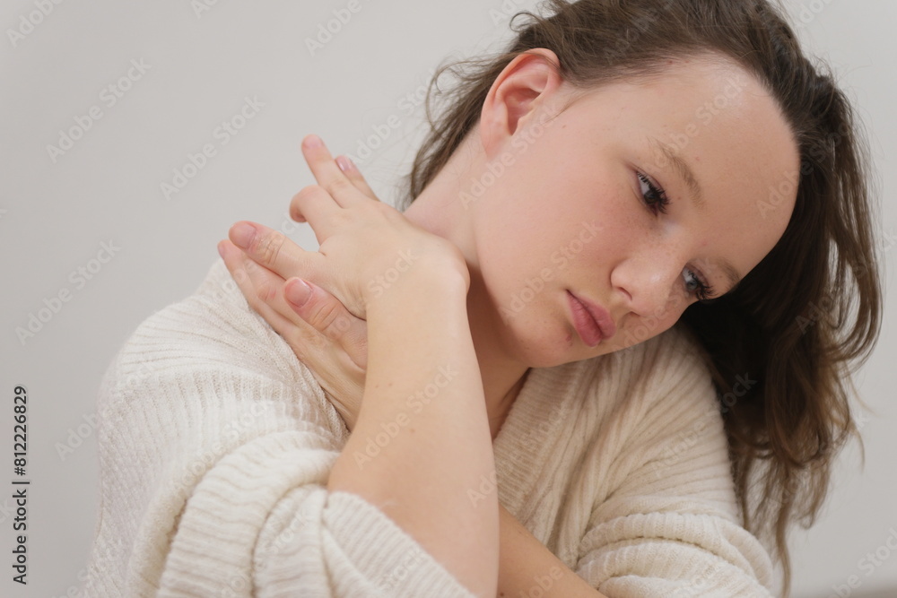 Neck massage. Young woman sitting on sofa and experiencing neck pain Neck massage. Young woman sitting on sofa and experiencing neck pain