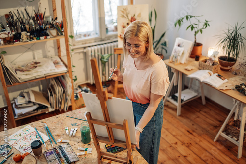 Artistic female hipster artist painting on easel at creative art studio