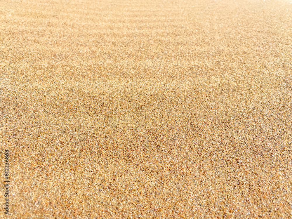 Fototapeta premium Clean sand on the beach on the summer with slight wave dunes. Background blur, bokeh. Selective focus.