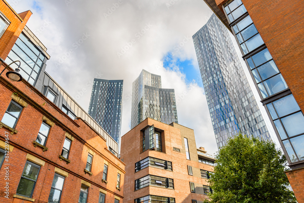 Fototapeta premium Renovated brick residential buildings overlooked by new glass apartment skyscrapers on a sunny summer day
