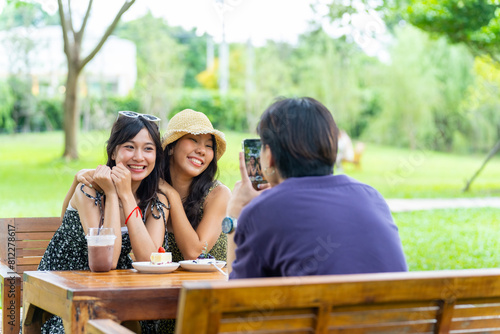 Happy young Asian man and woman enjoy outdoor lifestyle travel nature and cafe on summer holiday vacation. Generation z people friends mobile taking picture together at at outdoor restaurant.