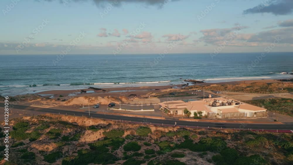 Drone view coastal road in sunset light. Serene ocean waves washing beach front Drone view coastal road in sunset light. Serene ocean waves washing beach front