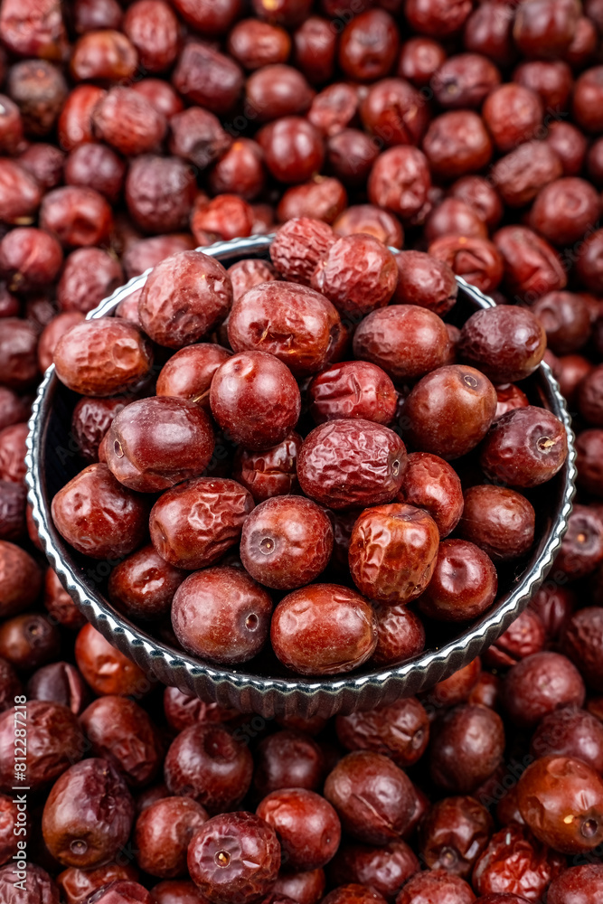 Fototapeta premium Fresh Jujube Fruits in a Metal Bowl on Pile Background, Close-up of fresh jujube fruits in a vintage metal bowl, surrounded by a pile of jujubes with a focused, glossy texture.