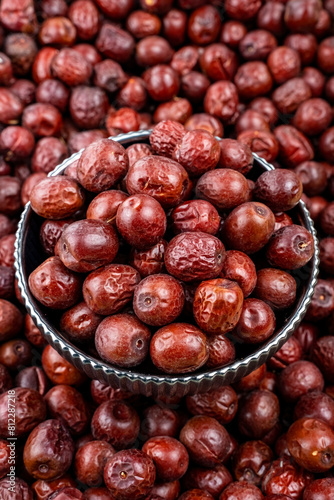 Fresh Jujube Fruits in a Metal Bowl on Pile Background, Close-up of fresh jujube fruits in a vintage metal bowl, surrounded by a pile of jujubes with a focused, glossy texture.