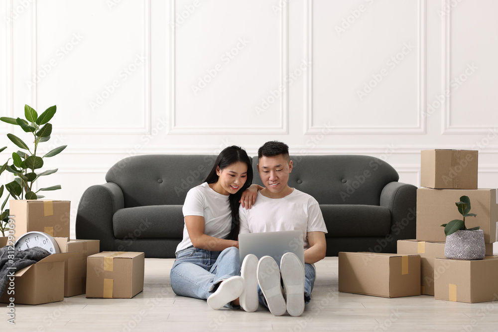 Happy couple with laptop on floor in their new apartment Happy couple with laptop on floor in their new apartment