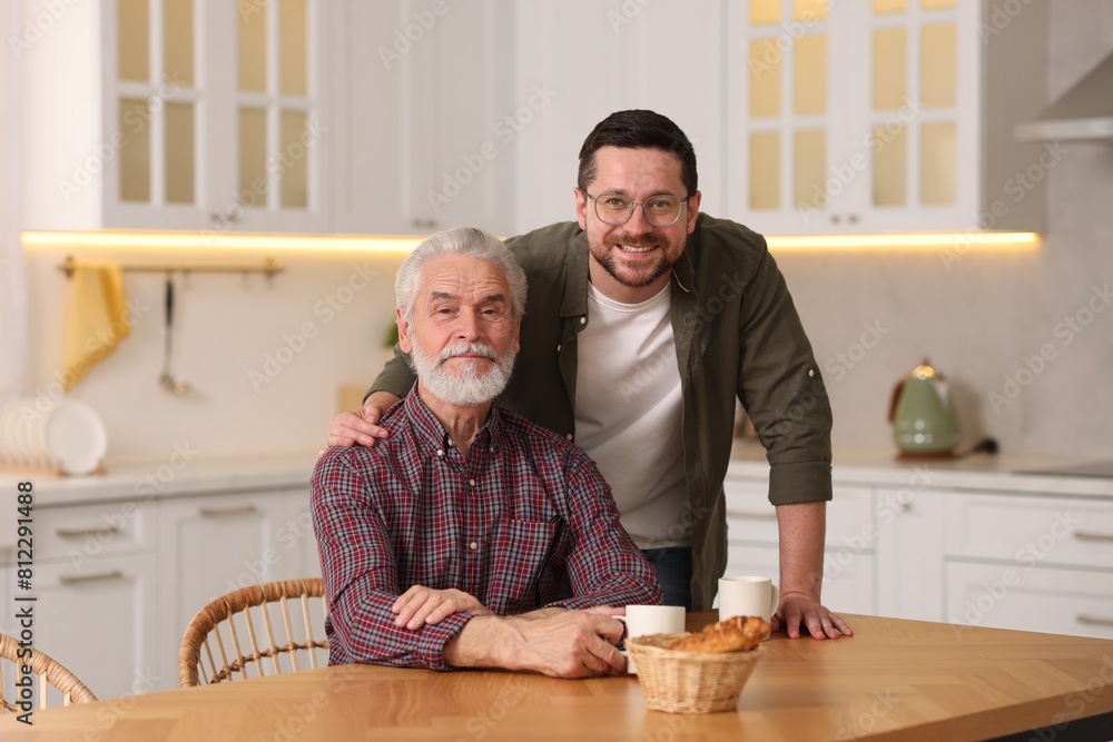 Happy son and his dad at wooden table in kitchen Happy son and his dad at wooden table in kitchen