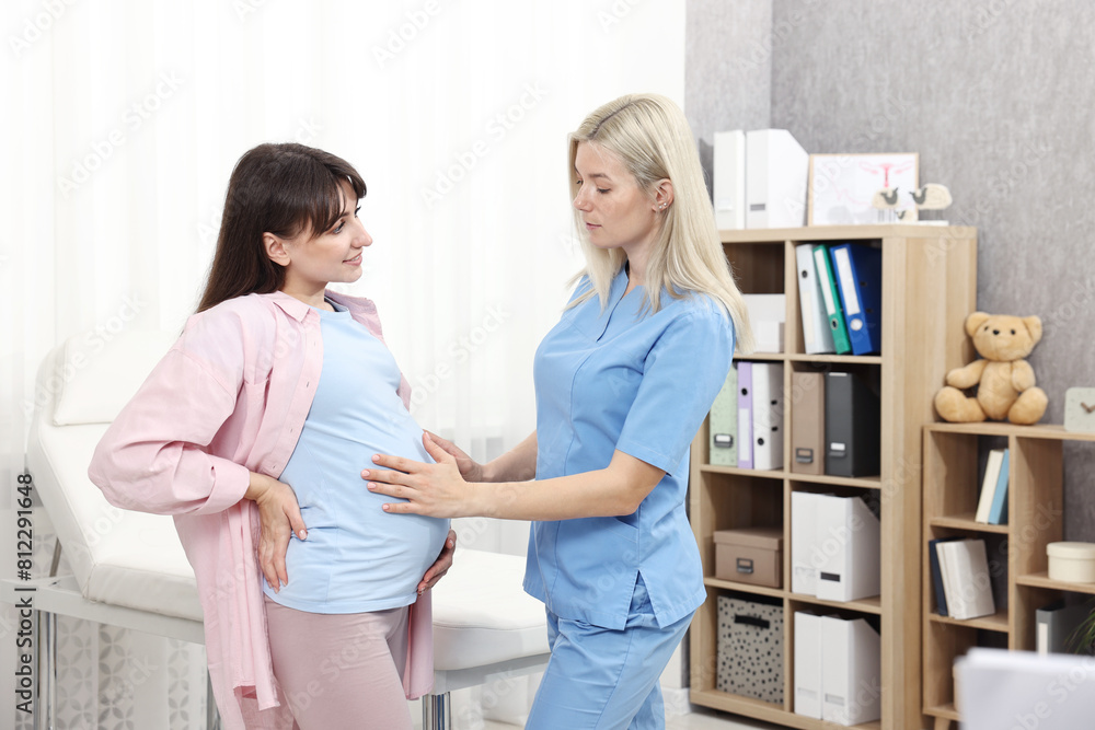 Pregnancy checkup. Doctor examining patient's tummy in clinic Pregnancy checkup. Doctor examining patient's tummy in clinic