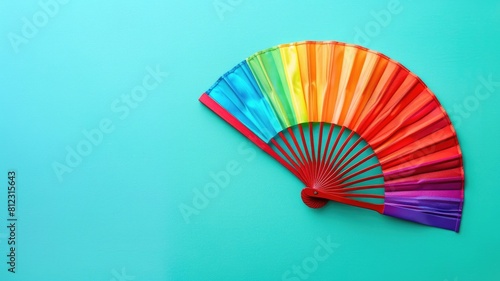 Multicolored hand fan opened on turquoise background