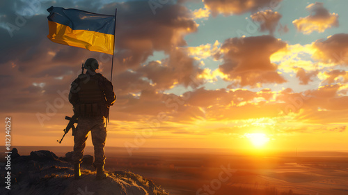 A soldier stands enjoying the sunrise with the Ukrainian flag flying next to him. National holiday, flag day, veterans day, memorial day, independence day, patriot day concept. photo