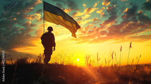 A soldier stands enjoying the sunrise with the Ukrainian flag flying next to him. National holiday, flag day, veterans day, memorial day, independence day, patriot day concept. photo