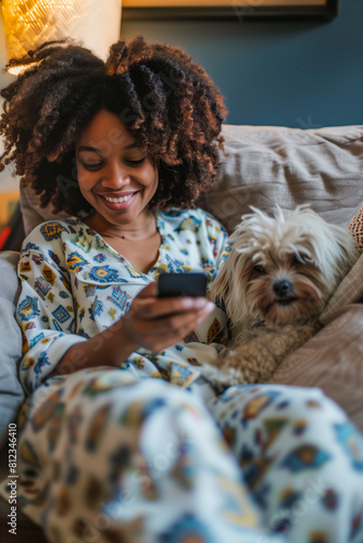 A woman is sitting on a couch with a dog and a cell phone