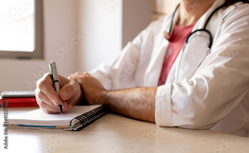 Short shot of a doctor in his office taking notes while listening to his patient. Medical care concept