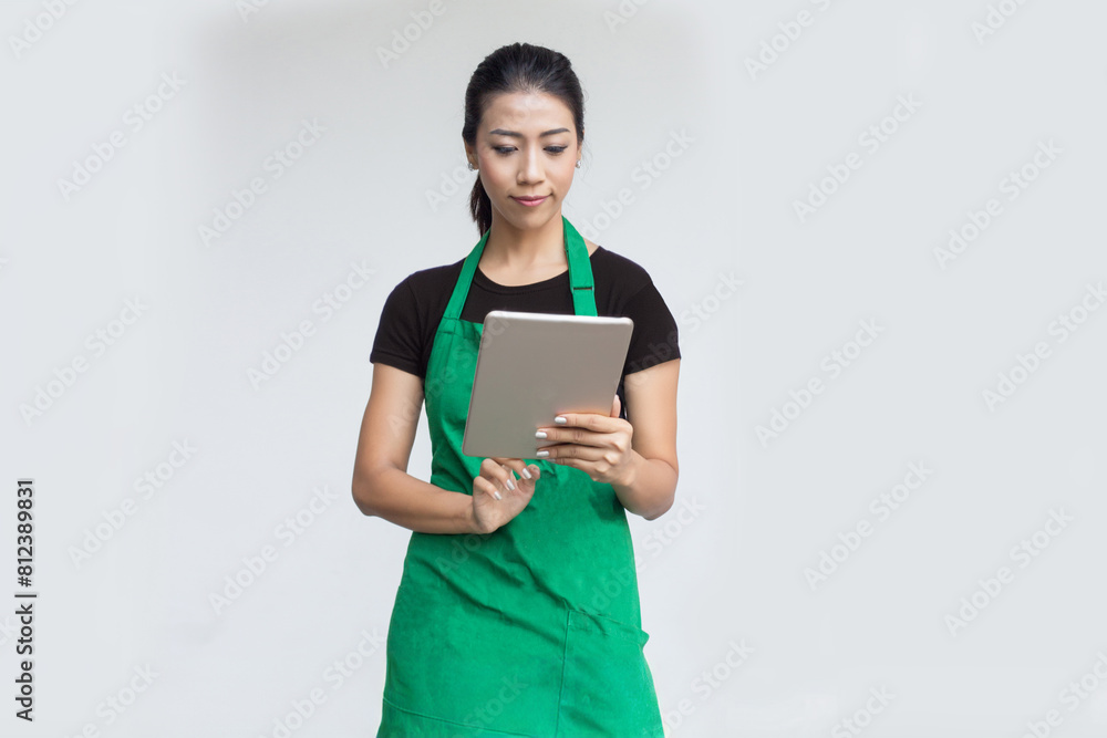 Asian woman model wearing apron look and touch tablet to check order or check stock in digital Asian woman model wearing apron look and touch tablet to check order or check stock in digital