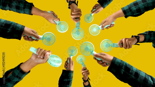 Hand holding small portable fan on isolated yellow background photo