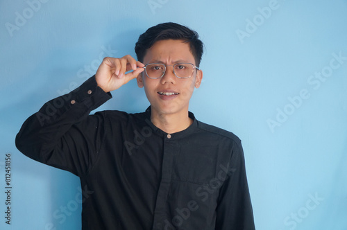 Asian young man wearing a black shirt smiling confident with hand touching his glasses frame photo