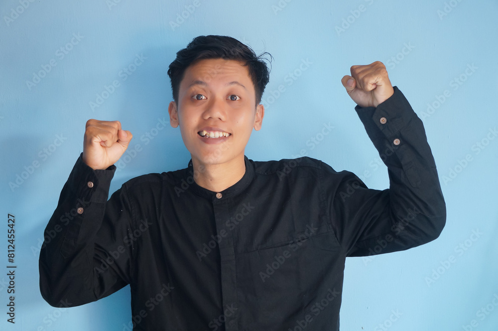 Fototapeta premium portrait of smiling happy asian young man with clenched fists