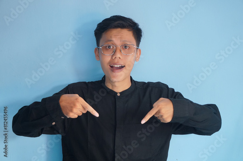 Asian young man smiling happy while pointing down photo