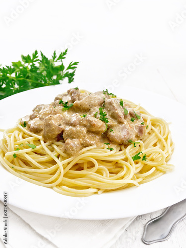 Meat in creamy sauce with spaghetti on table