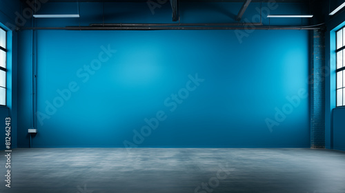 Spacious industrial-style room with vibrant blue walls and empty concrete floor for versatile use