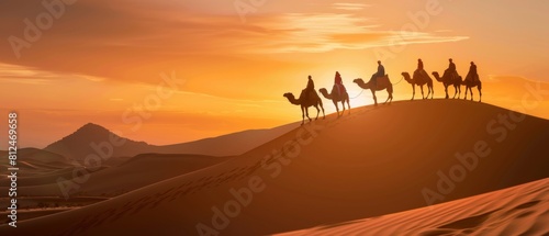 Silhouetted Camel Caravan on Sand Dune at Sunset.
