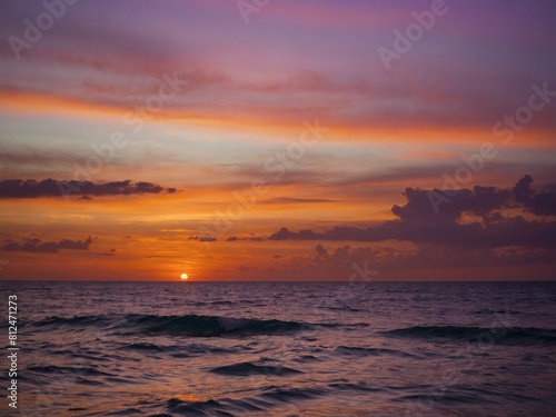 A picturesque moment, Sunset bathes the calm ocean in hues of orange, pink, and purple, creating a stunning vista.
