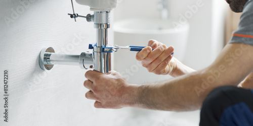 Professional plumber fixing a bathroom sink photo
