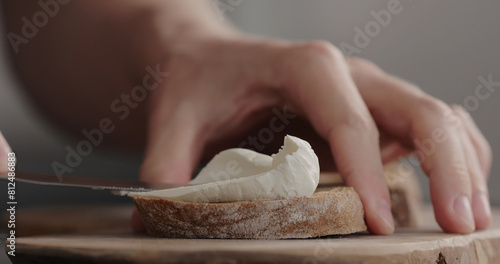 Foto man hand spreading cream cheese on dark ciabatta